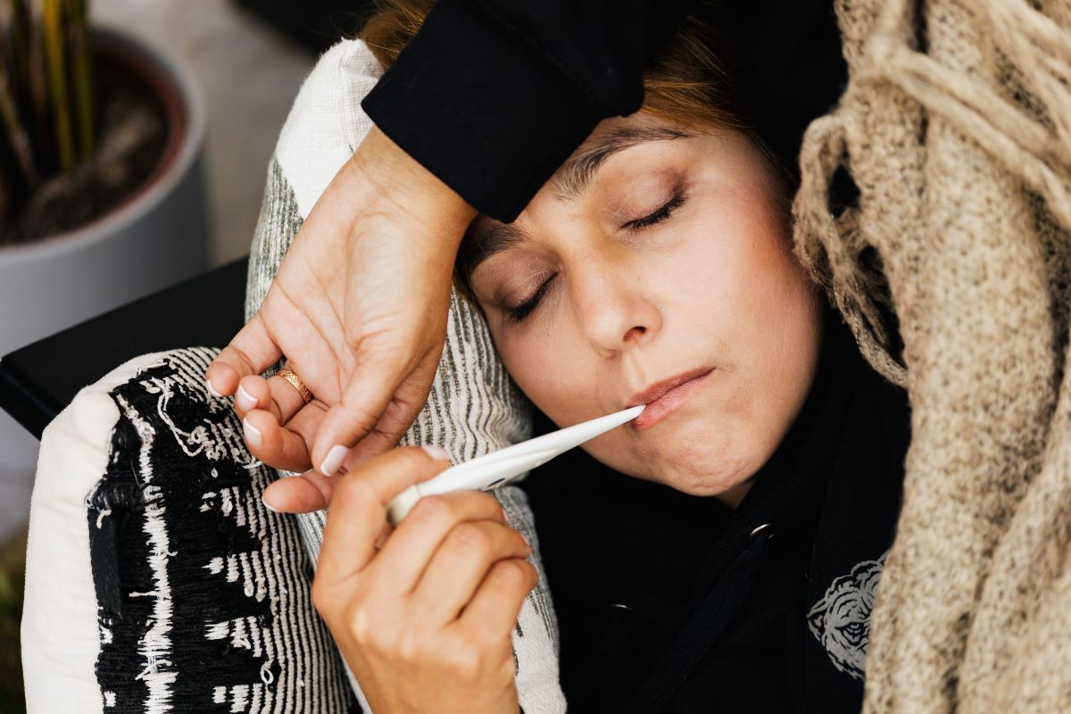 sick woman with a thermometer placed in her mouth